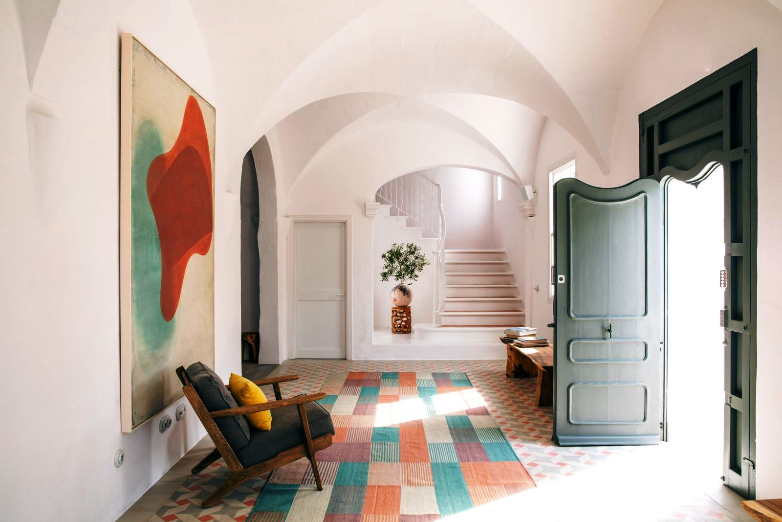 hallway with arched ceiling an open green door, wooden chair four green chairs and a long table with food and wine on the roof terrace at luxury villa Casa Benedicta in Menorca 