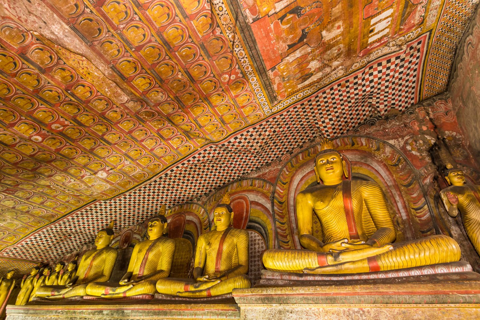 Interior of Sri Lanka's Dambulla Caves with buddhas and ornate paintings