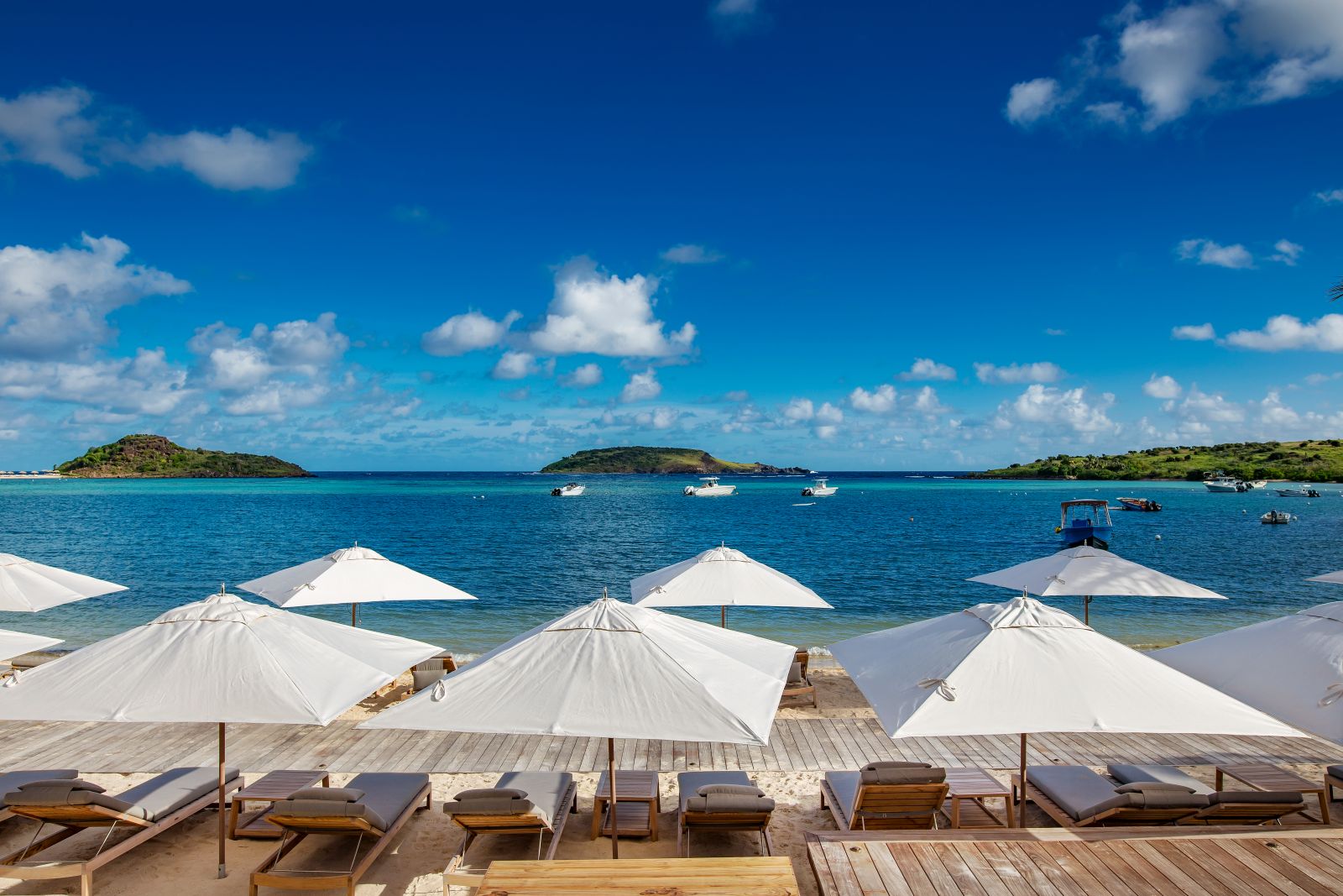 Sun loungers with white sun umberllas on the beach at Le Barthelemy Hotel & Spa in St Barths
