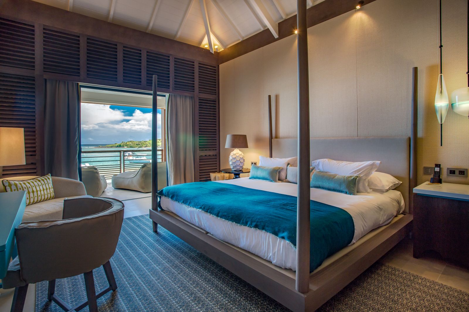 A double bedroom with four poster bed and outside balcony at Le Barthelemy Hotel & Spa in St Barths