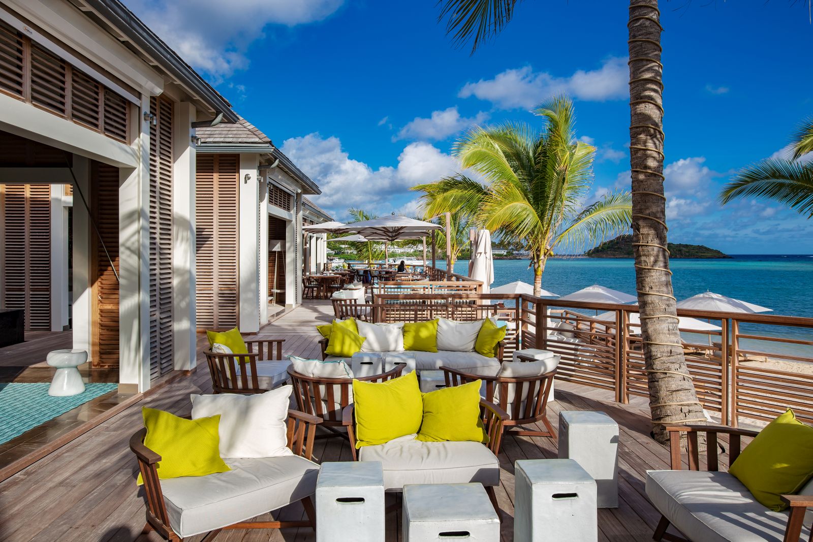 Outdoor seating area with white chairs and yellow cushions at the Le Barthelemy Hotel & Spa in St Barths