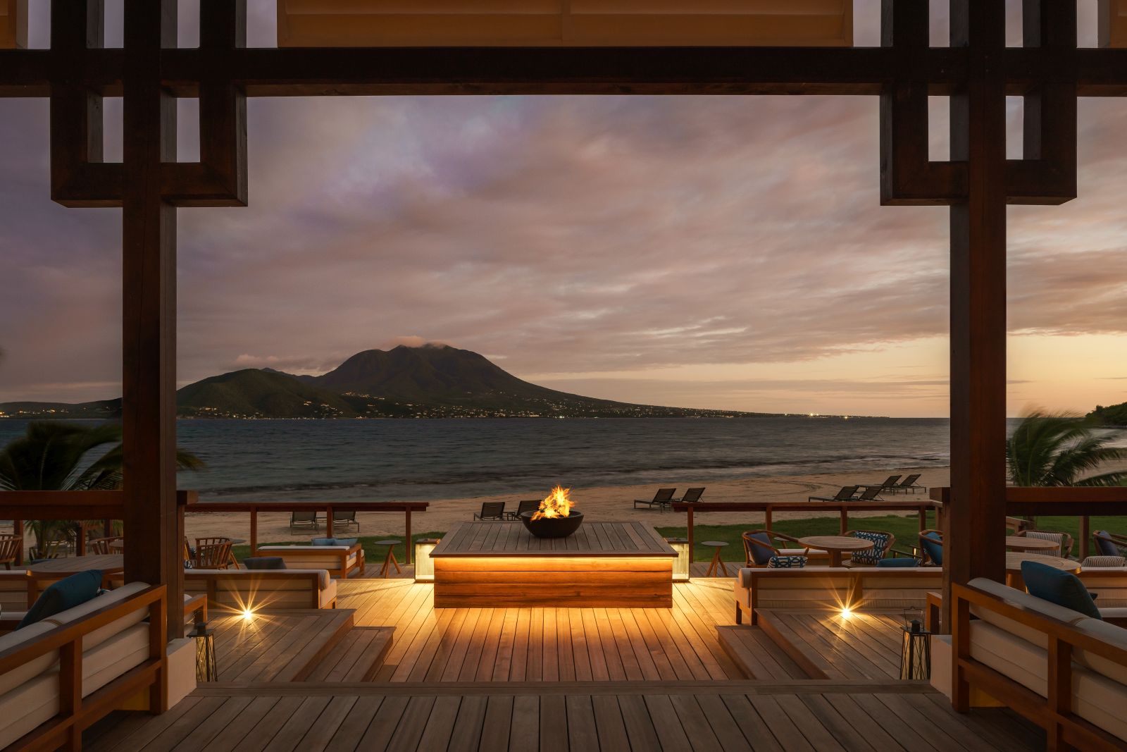 A decking area with chairs, tables and oustide fireplace at the Park Hyatt St. Kitts Christophe Harbour Hotel