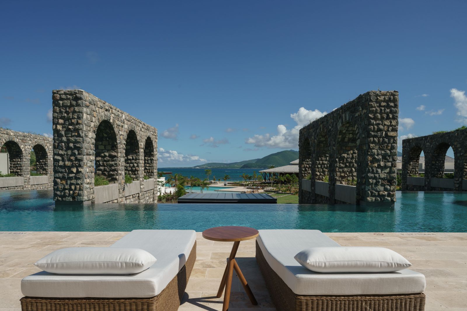 Two sun beds with a view of the sea between two stone ramparts at the Park Hyatt St. Kitts Christophe Harbour Hotel