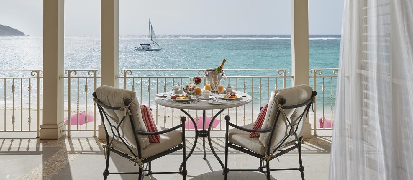 two chairs and a bottle of champagne on a balcony overlooking the ocean