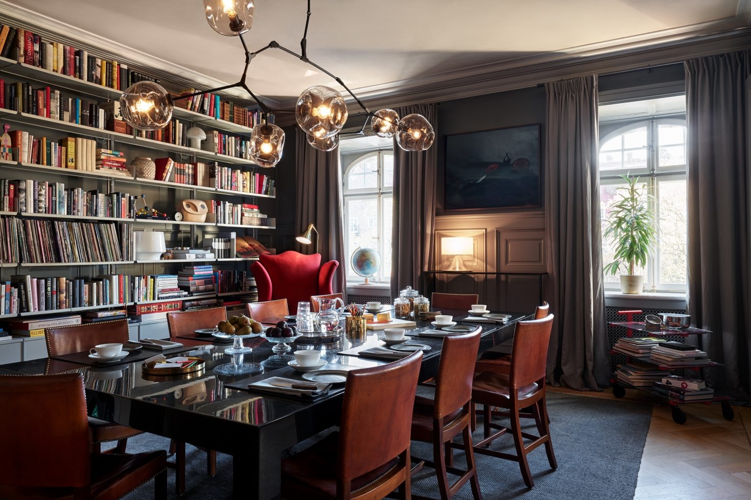 Dining room set for brakfast with big windows and a wall-covering book shelf
