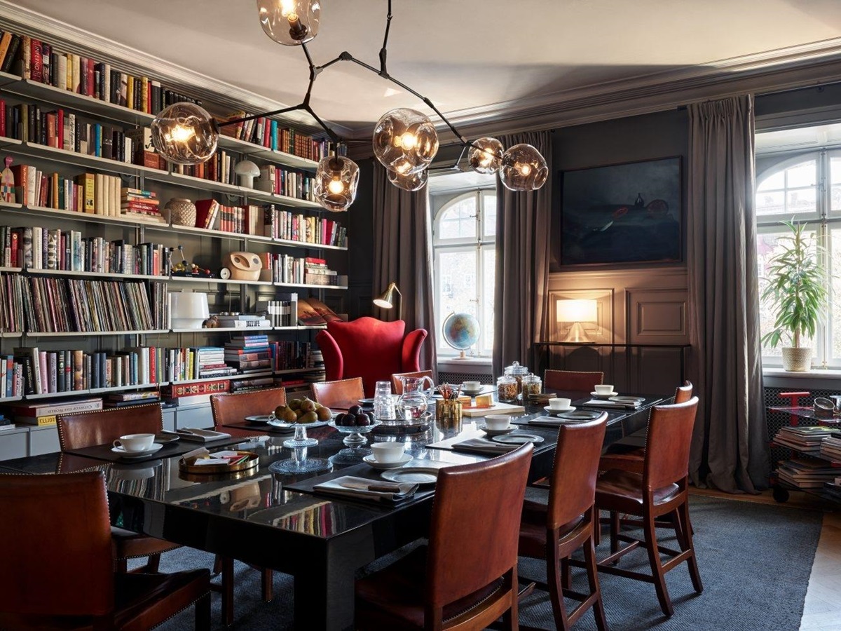 Dining room set for brakfast with big windows and a wall-covering book shelf