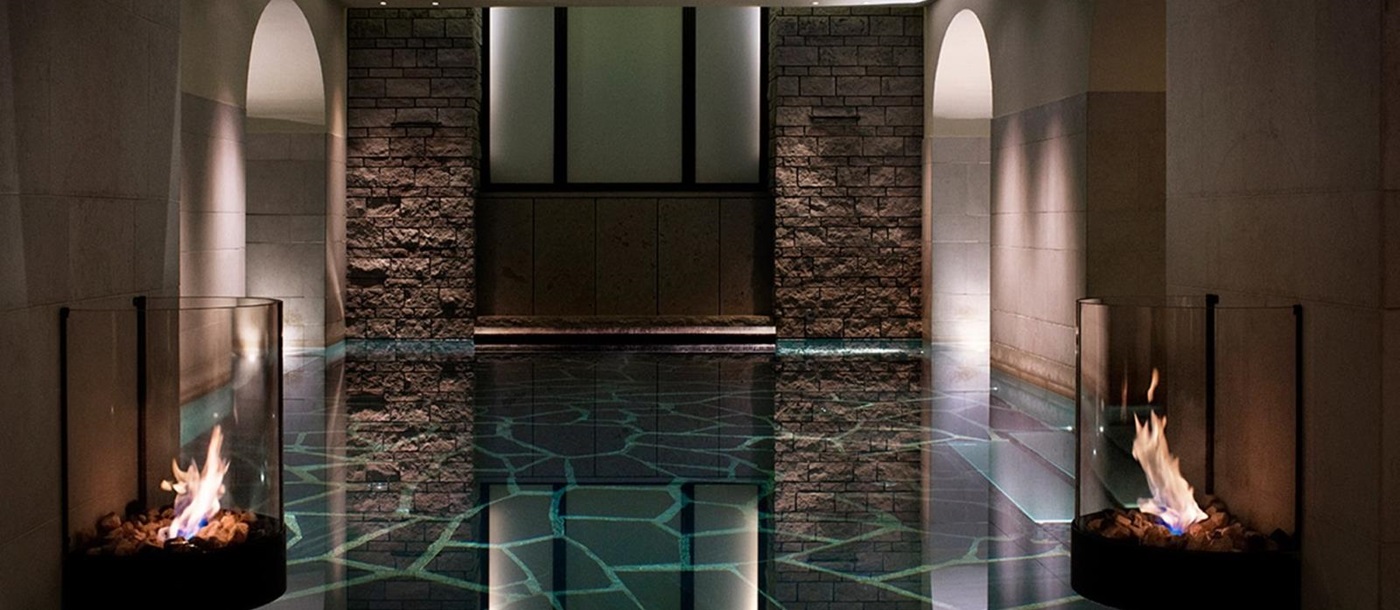 Indoor pool with mood lighting and fire in glass bowls