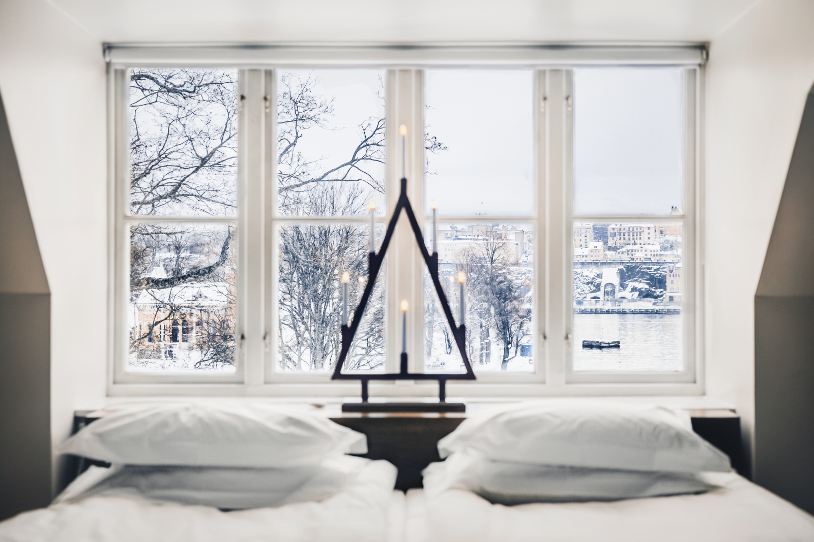Looking out through a window over a double bed onto the snowy houses and water