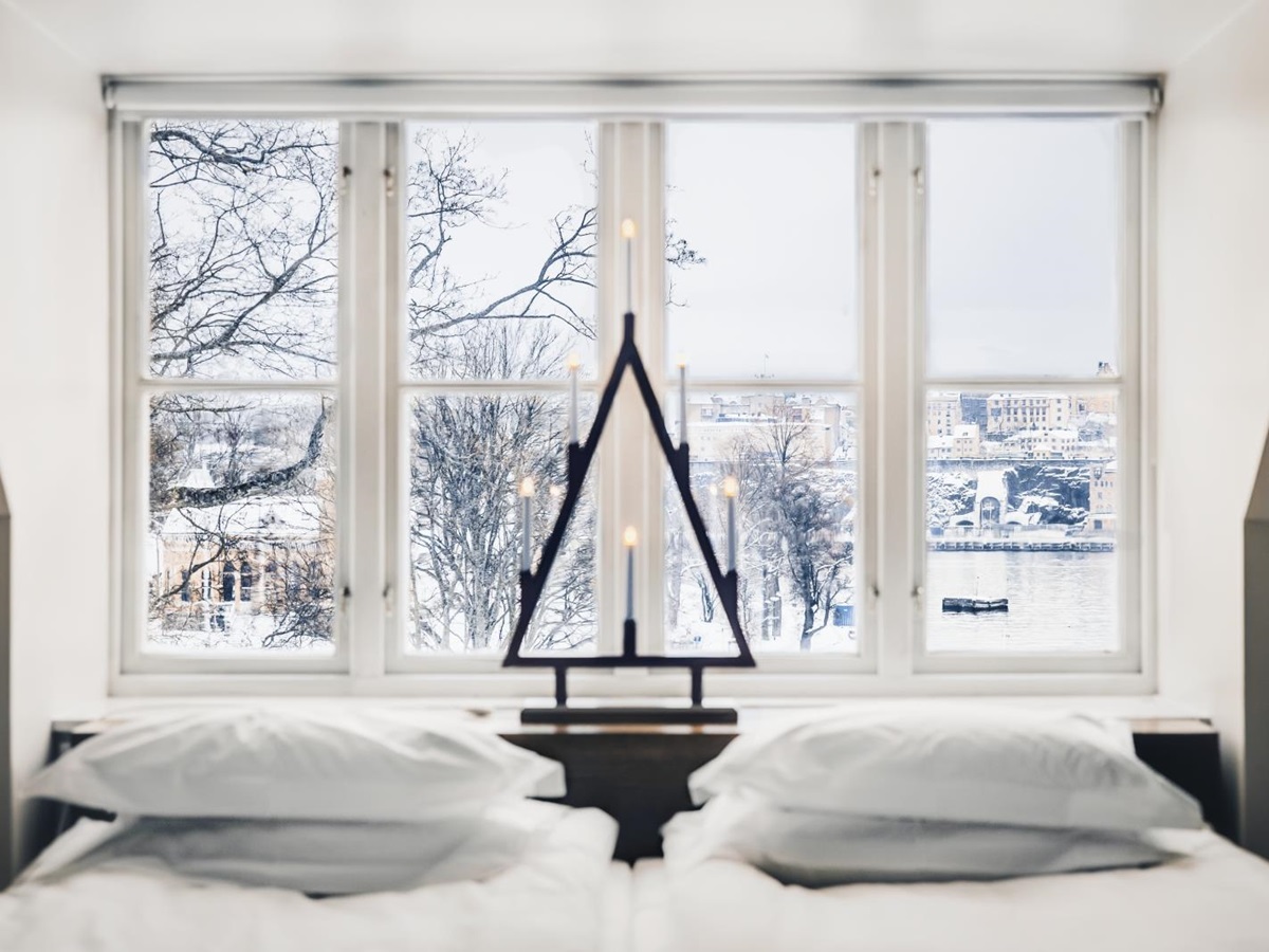 Looking out through a window over a double bed onto the snowy houses and water