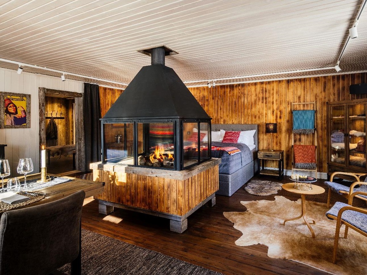 Cosy bedroom with indoor fireplace in luxury Loggers Lodge hotel in Sweden