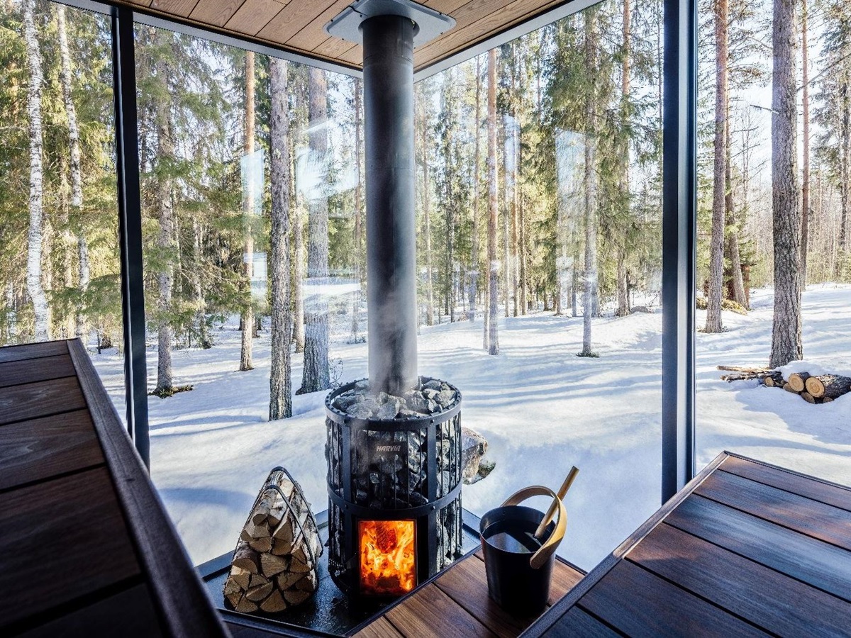 Interior view of private sauna with forest and snow views at luxury Loggers Lodge hotel in Sweden