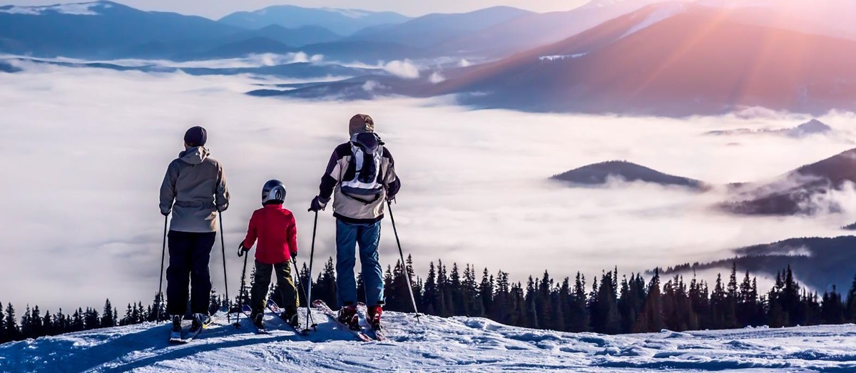 A couple and child on skis looking out to a view of misty mountain tops
