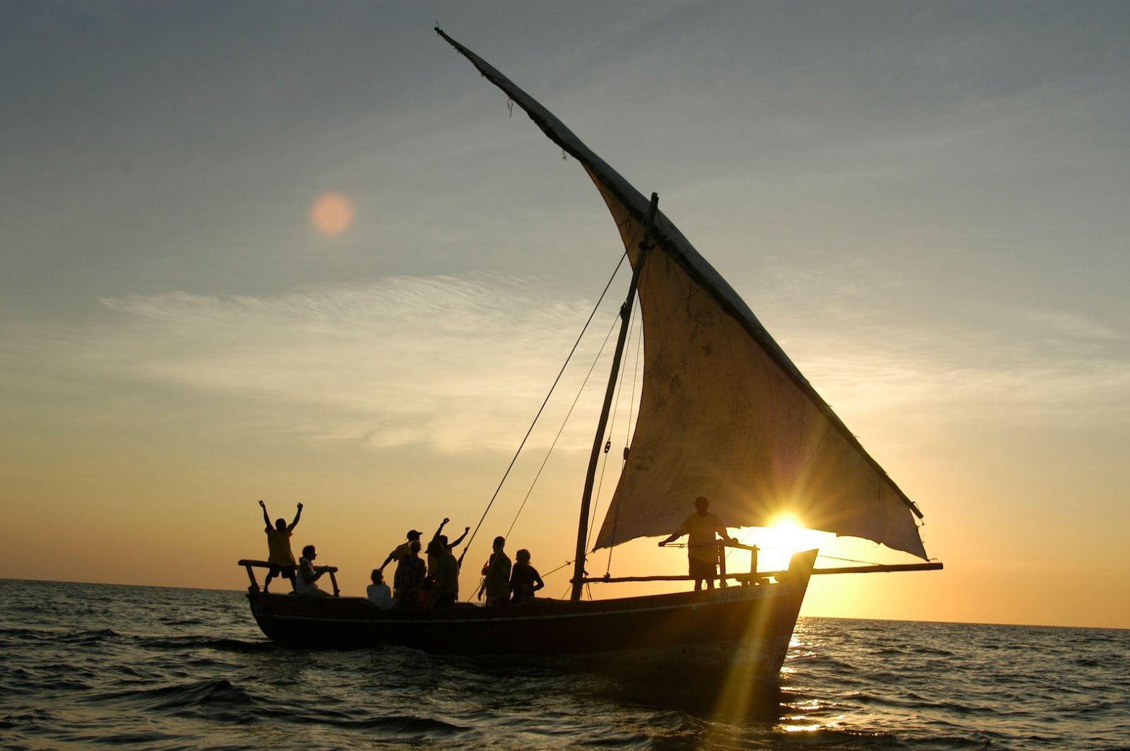 Guests enjoying a sunset cruise on a traditional dhow at luxury hotel Fundu Lagoon on Zanzibar