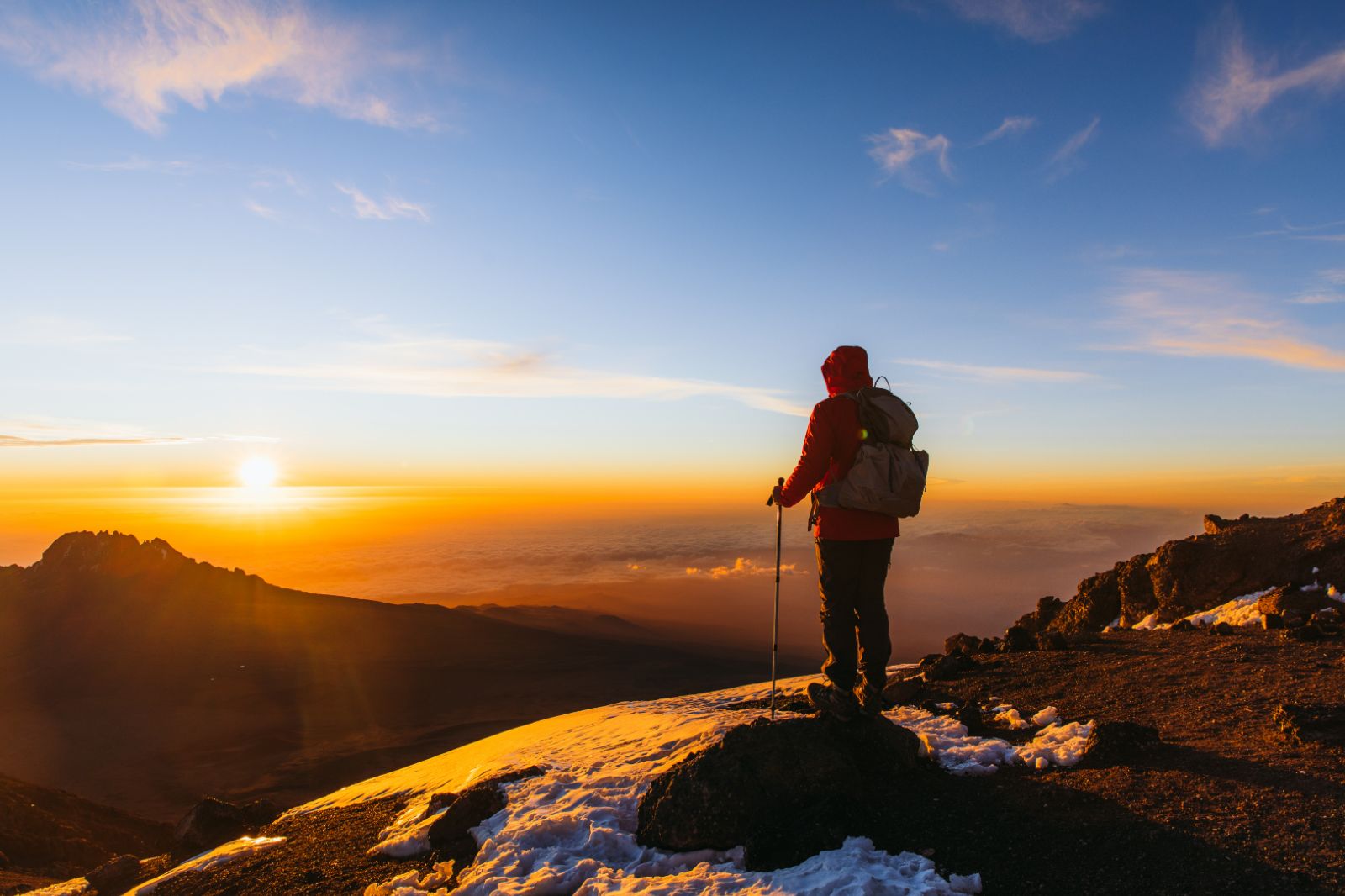 A climber at the summit of Mount Kilimanjaro at sunrise