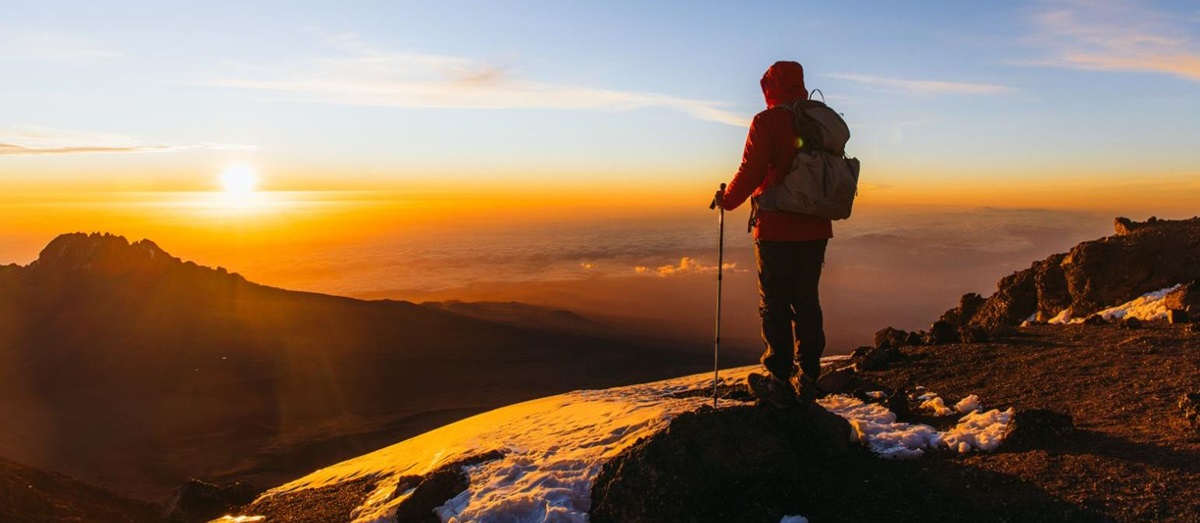 A climber at the summit of Mount Kilimanjaro at sunrise