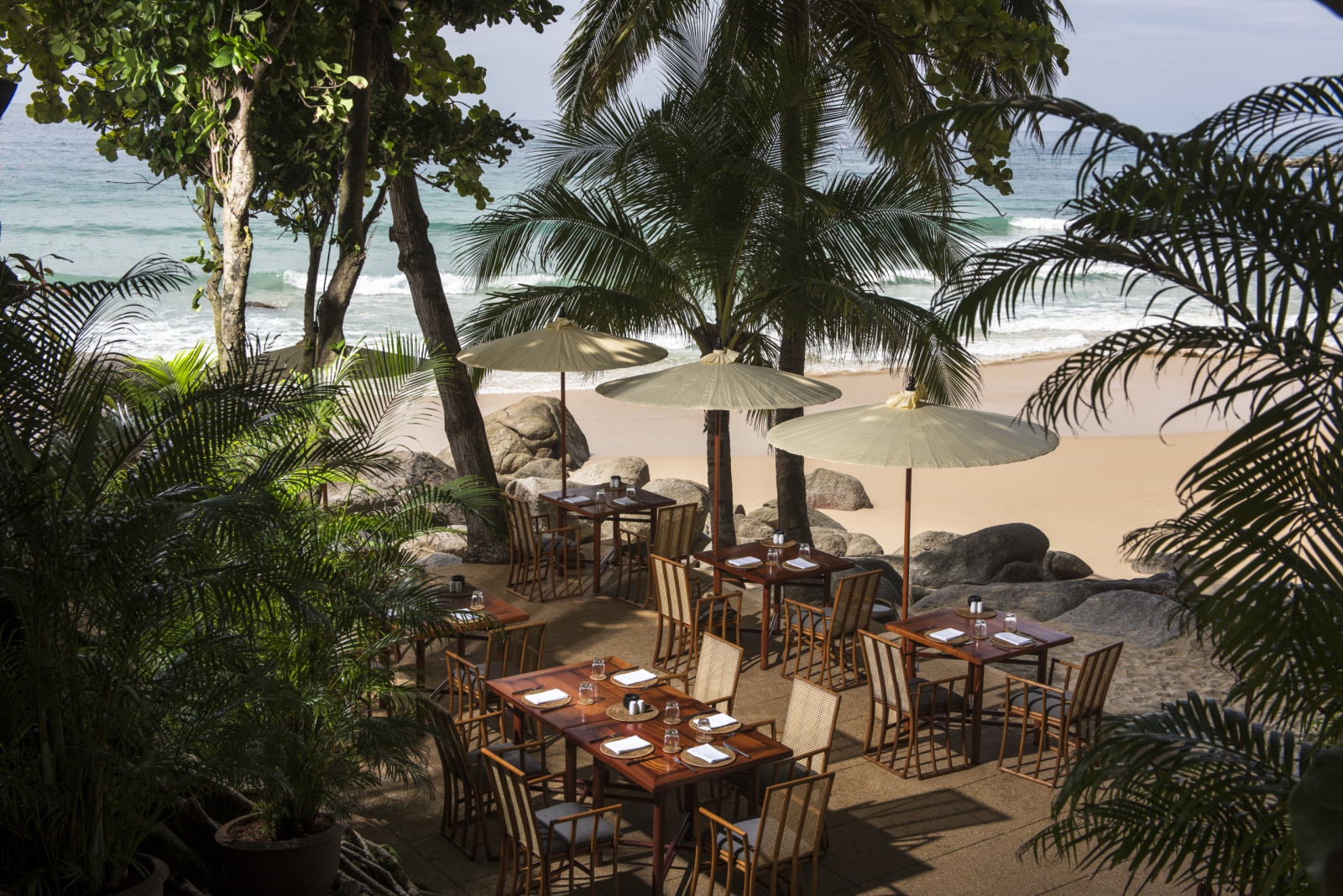 Beach dining set-up with parasols at Amanpuri