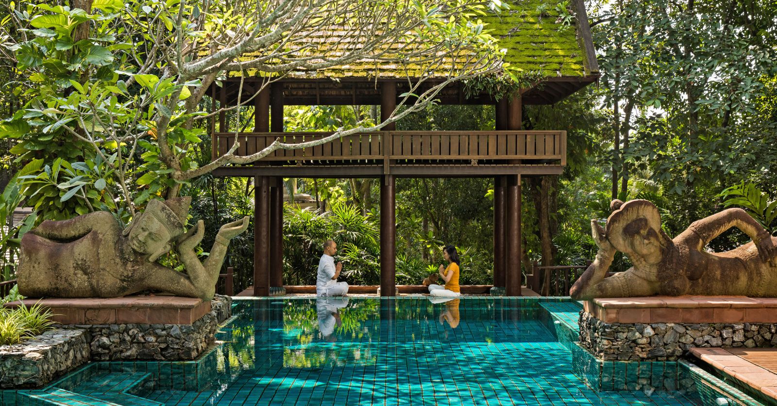 Guests practicing yoga next to the pool at luxury resort Four Seasons Chiang Mai