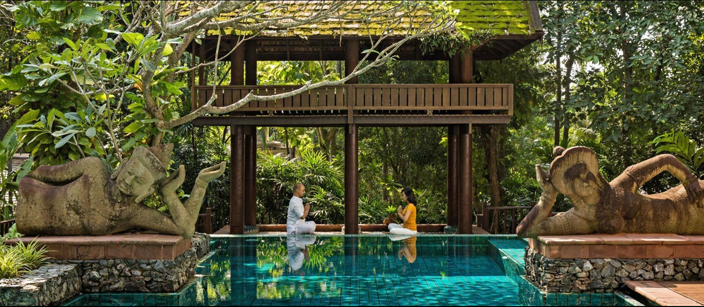 Guests practicing yoga next to the pool at luxury resort Four Seasons Chiang Mai
