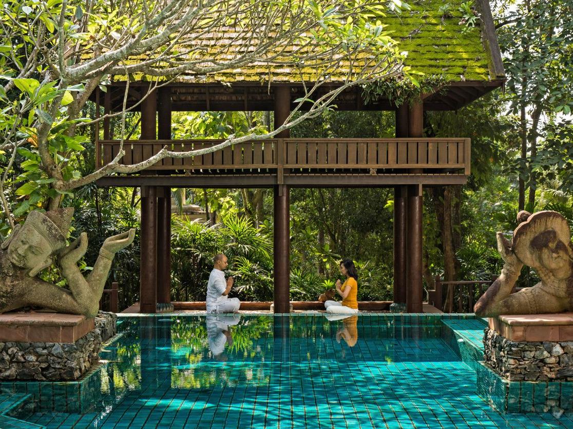 Guests practicing yoga next to the pool at luxury resort Four Seasons Chiang Mai
