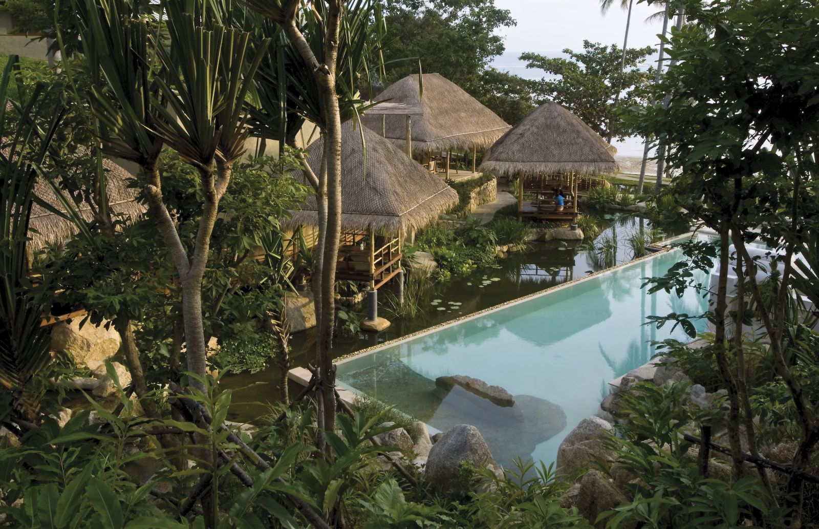 Pool and rooms hidden in the lush gardens at at luxury wellness resort Kamalaya in Thailand