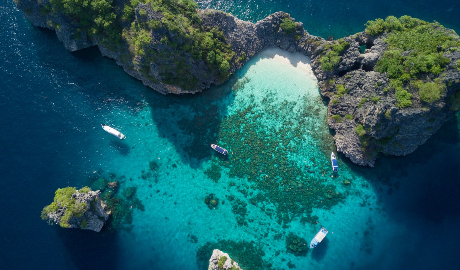 Islands surrounded by bright blue water and coral 