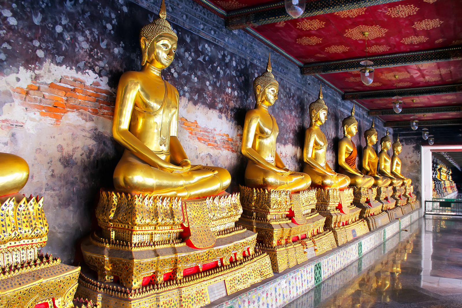 Row of golden buddhas in a temple in Bangkok, Thailand