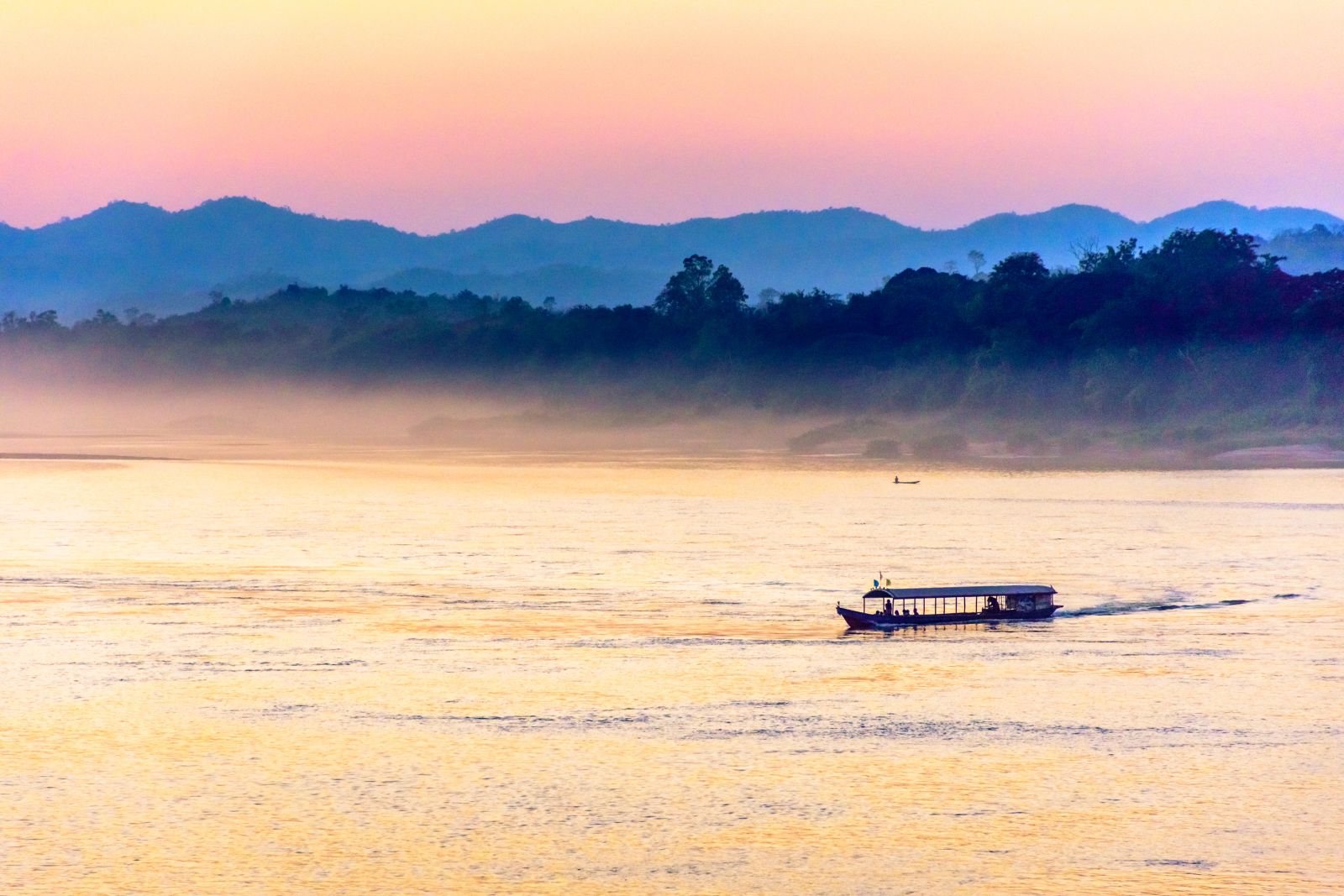 A boat crusing the Mekong River in Thailand at sunset
