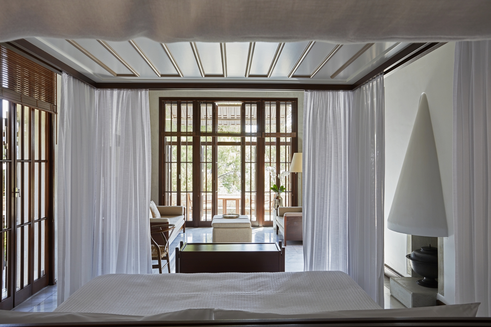 Spacious bedroom in a pavilion at luxury hotel Amanruya, Turkey, with four poster bed, seating area and floor-to-ceiling windows
