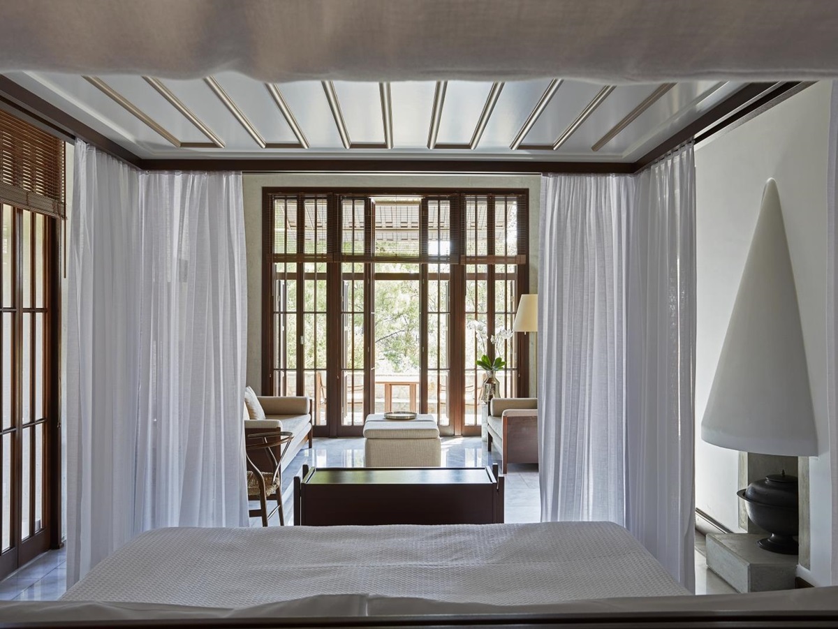 Spacious bedroom in a pavilion at luxury hotel Amanruya, Turkey, with four poster bed, seating area and floor-to-ceiling windows