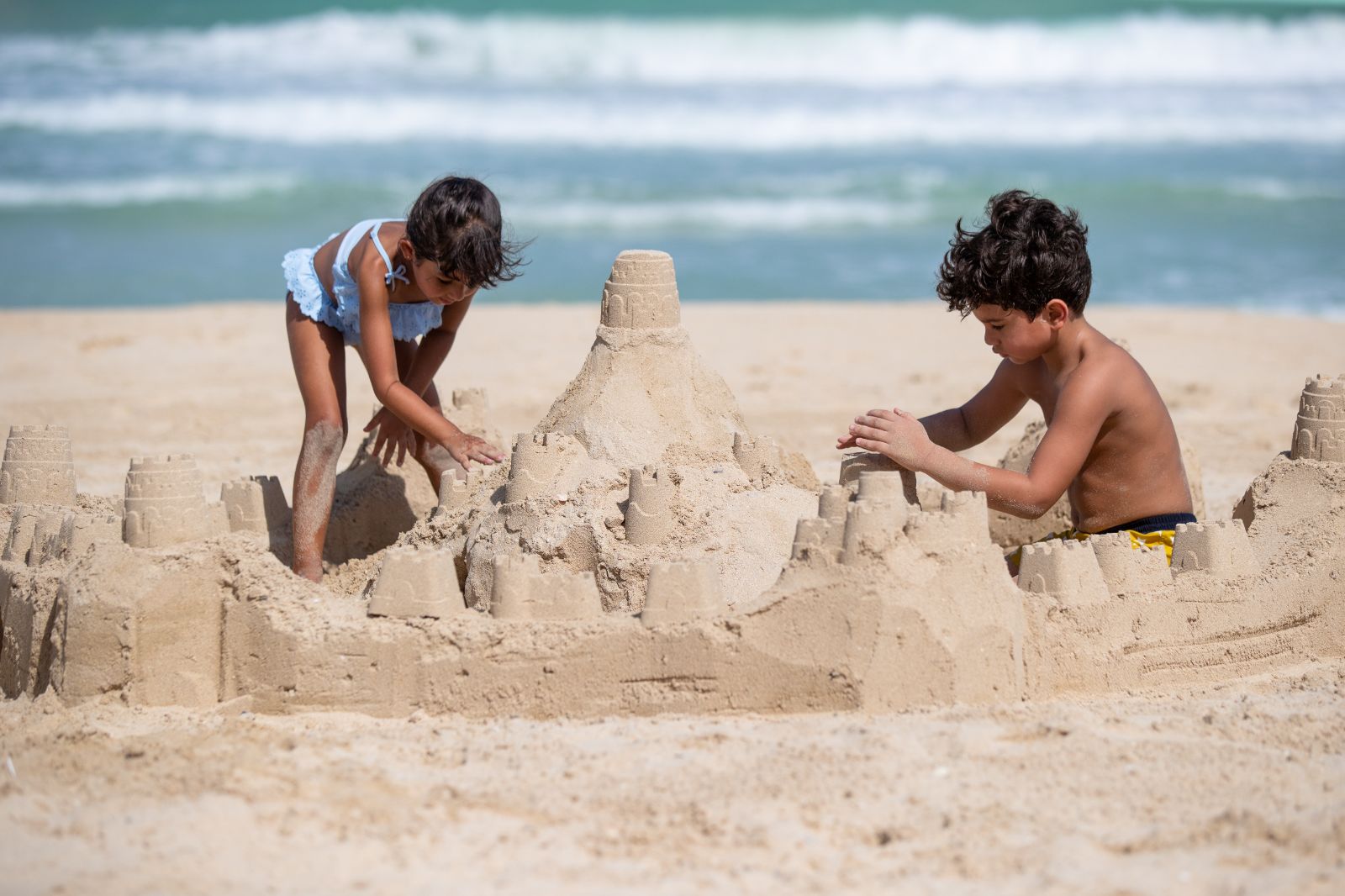 Children building a sandcastle on the beach at the Jumeirah Mina A Salam in Dubai