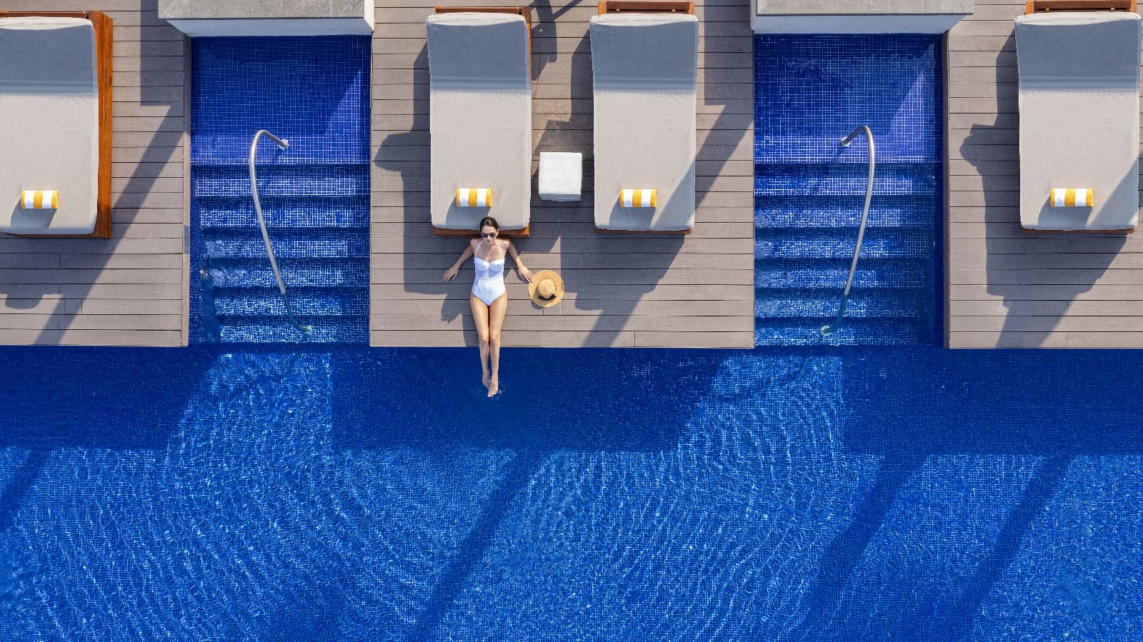 Aerial view of a guest laying by the pool at luxury beach resort The Oberoi Al Zorah in the United Arab Emirates