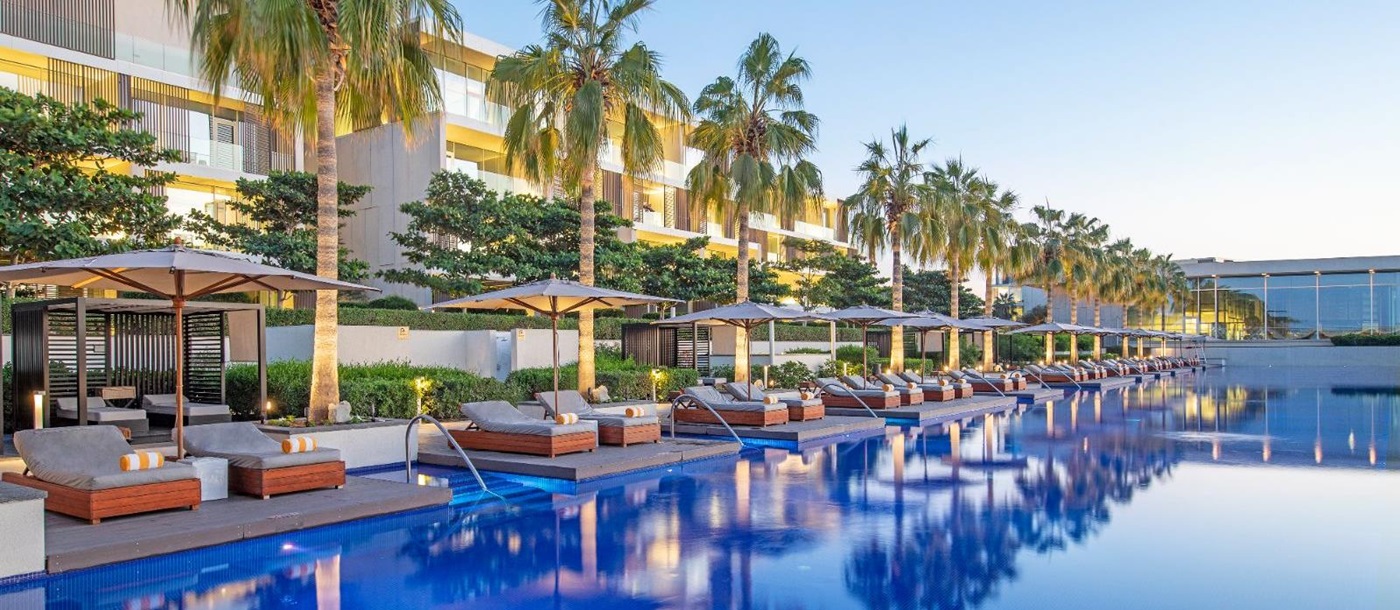 Palm-lined pool at luxury beach resort The Oberoi Al Zorah in the United Arab Emirates