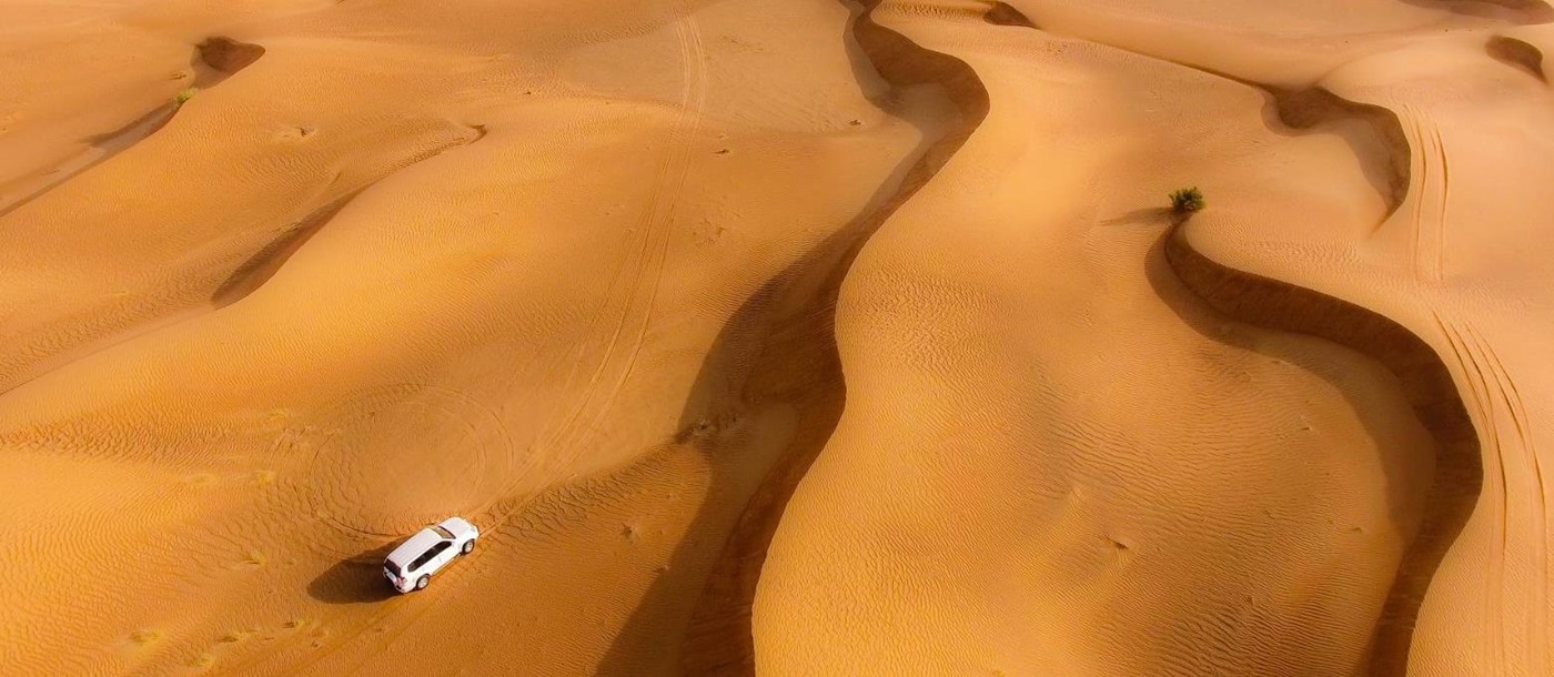 Aerial view of jeeps driving over the dunes in the Dubai desert