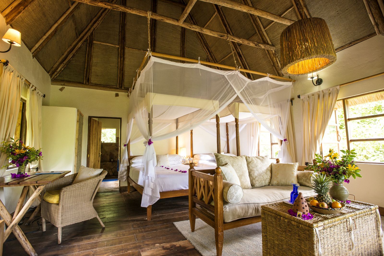 A double bedroom at Bwindi Lodge in Uganda with a four poster bed and furniture.