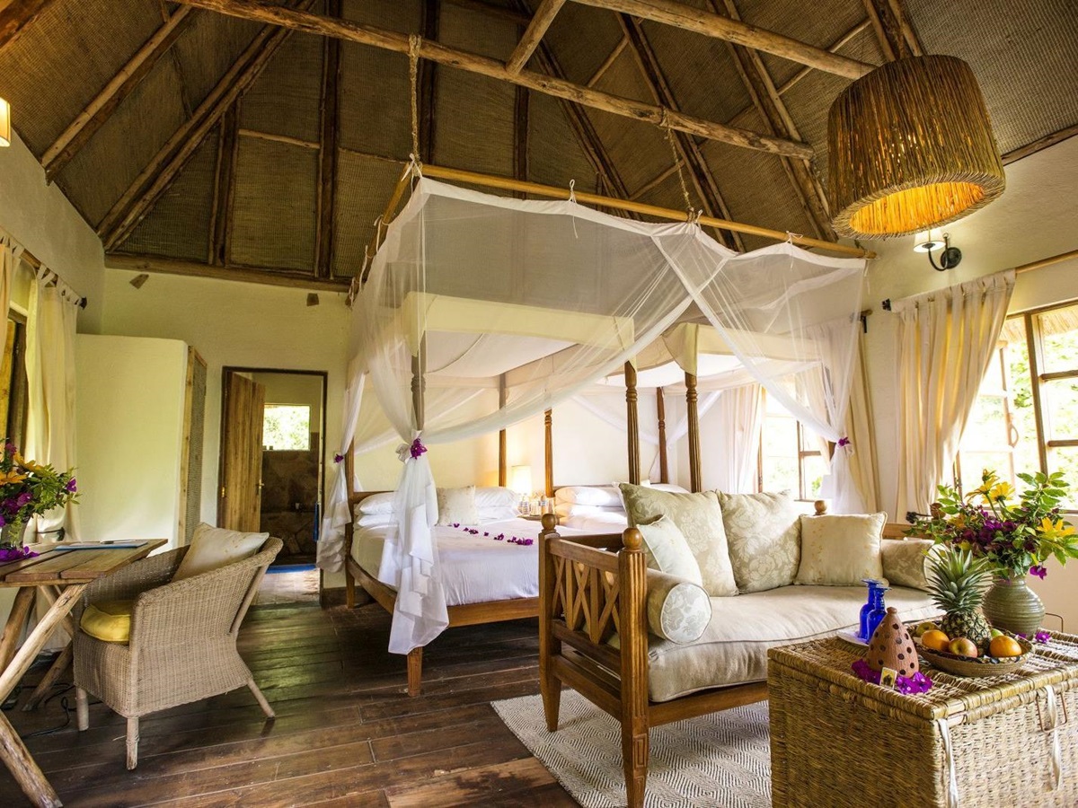 A double bedroom at Bwindi Lodge in Uganda with a four poster bed and furniture.