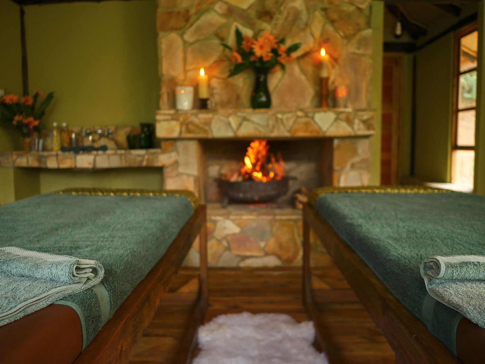 Two beds in front of a fireplace in the spa at Bwindi Lodge in Uganda.