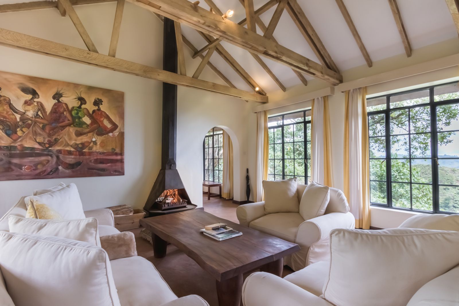 Living area with white comfy chairs and coffee table  in a bedroom at Clouds Mountain Gorilla Lodge in Uganda