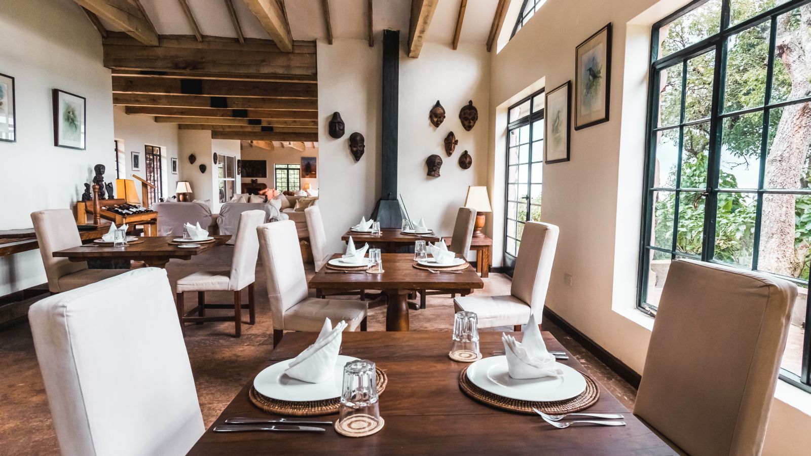 A wooden table set for dinner in the dining room at Clouds Mountain Gorilla Lodge in Uganda