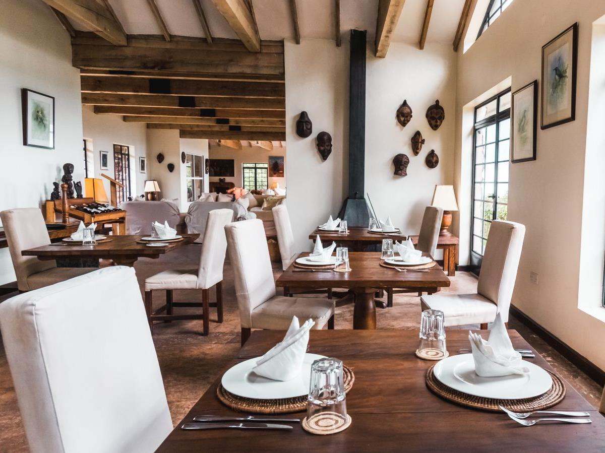 A wooden table set for dinner in the dining room at Clouds Mountain Gorilla Lodge in Uganda