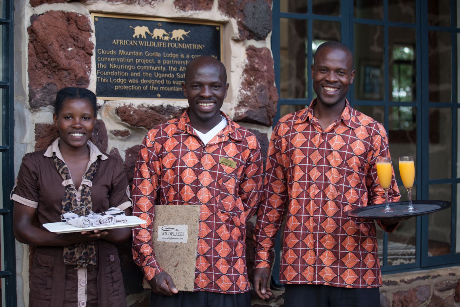 Three members of staff, one woman and two men, at Clouds Mountain Gorilla Lodge in Uganda