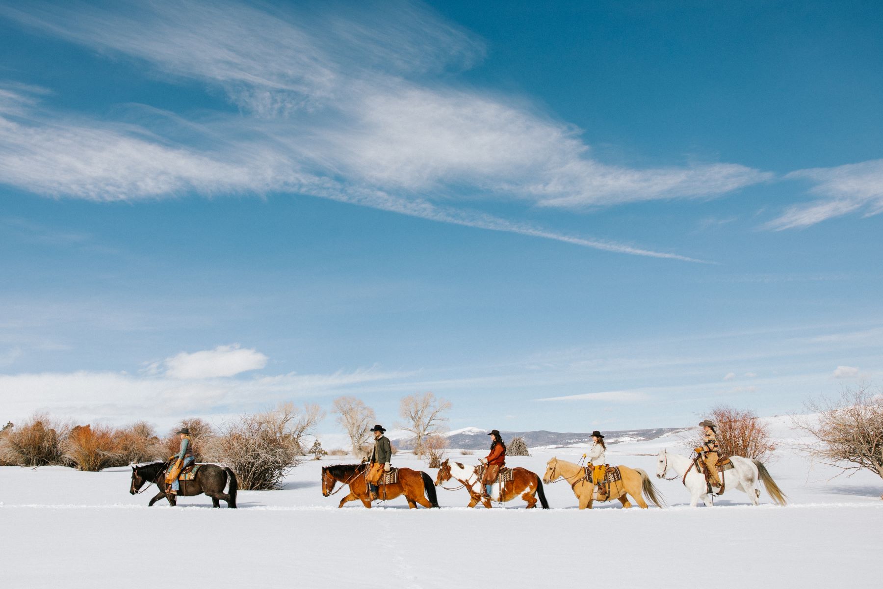 Brush Creek Ranch guests riding through the snow during a winter holiday in Wyoming