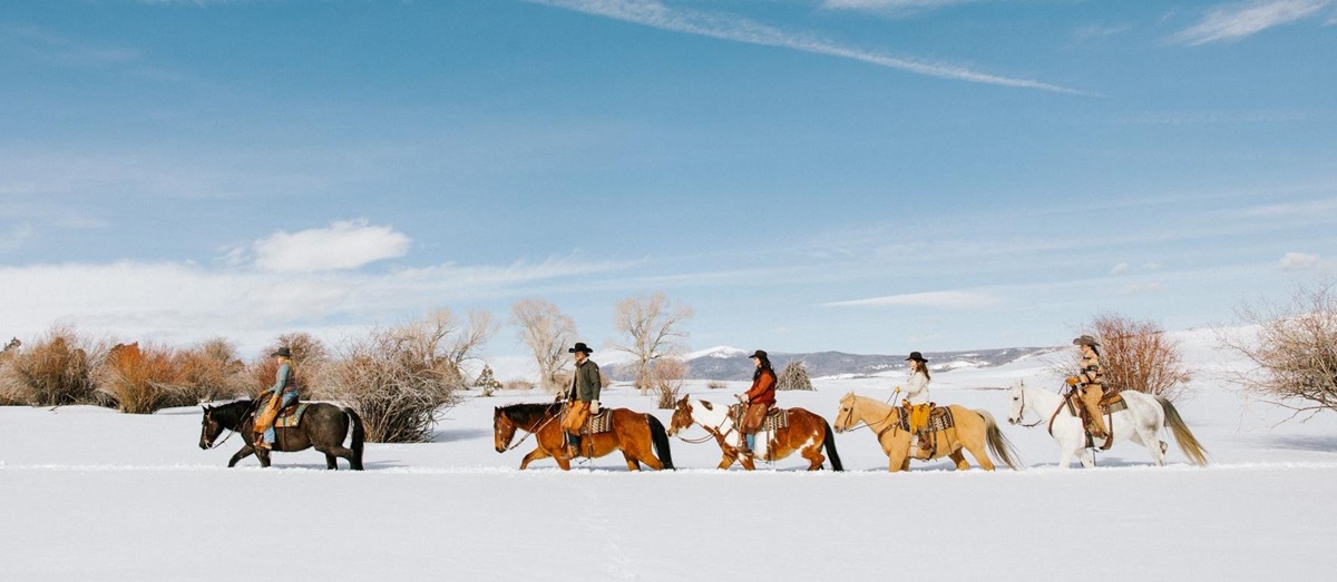 Brush Creek Ranch guests riding through the snow during a winter holiday in Wyoming