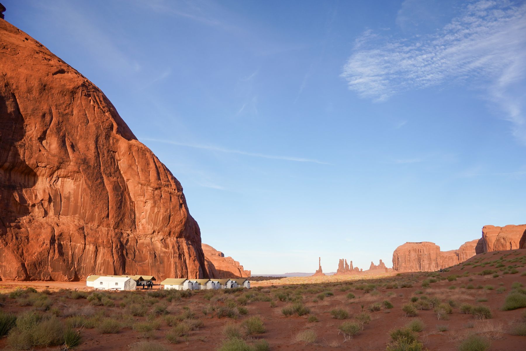 An EXP Journeys private camp at the foot of a red cliff in Monument Valley USA