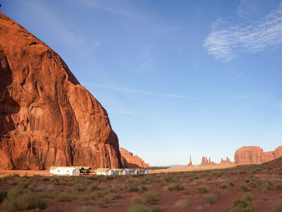 An EXP Journeys private camp at the foot of a red cliff in Monument Valley USA