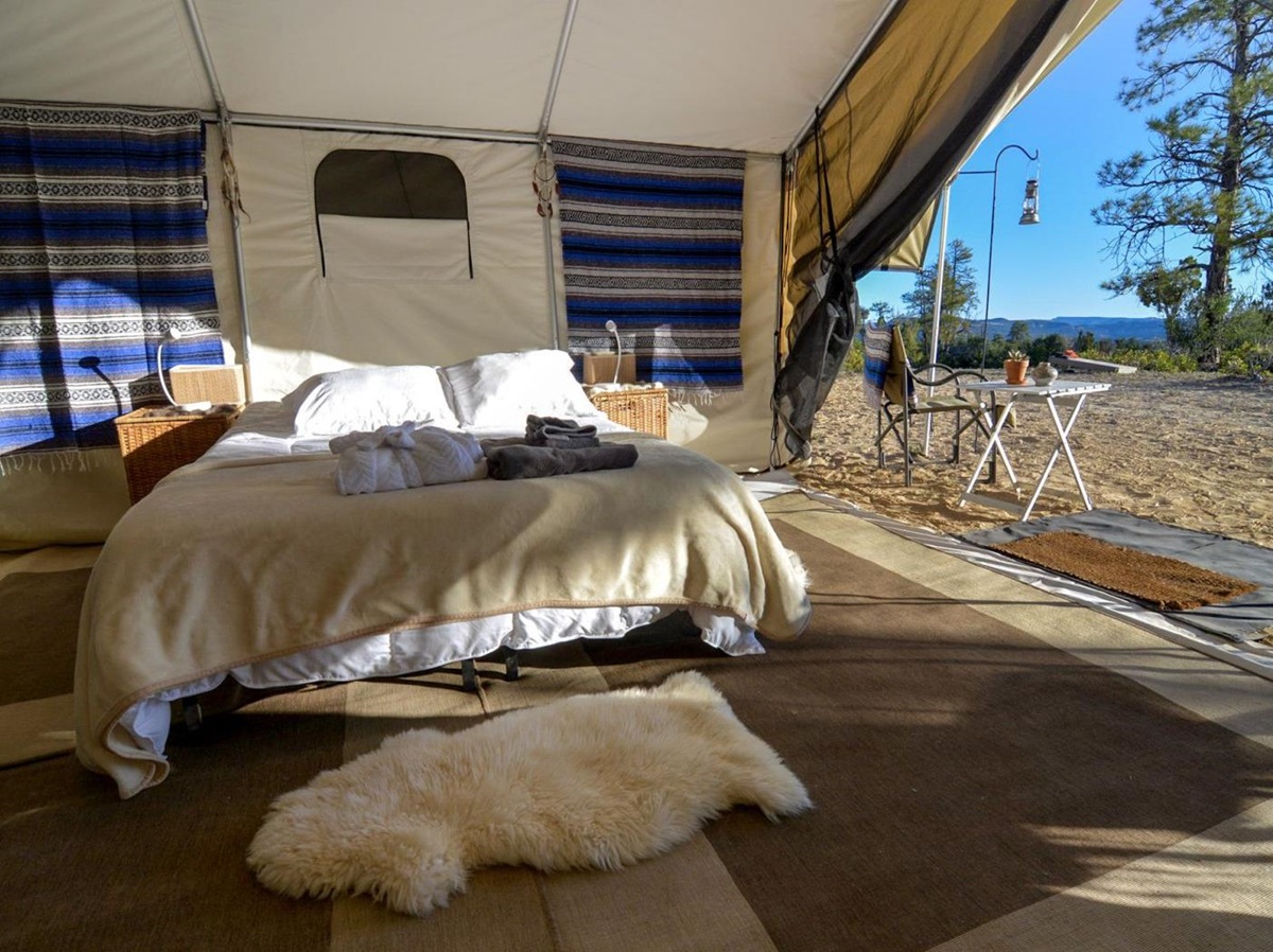 King bed in a tent at a private camp in Yellowstone National Park with outdoor table and views over the park