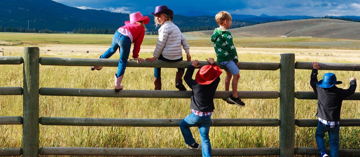 Children climbing a fence near Paws Up Ranch, USA