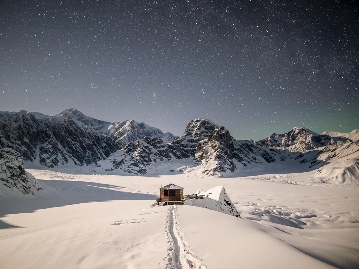 Starry sky with the chalet being lit with moonlight