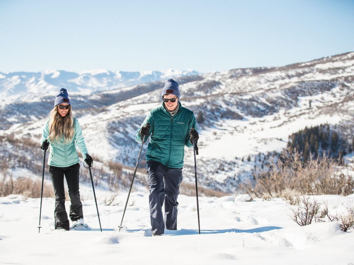 A couple walking through snow with snowshoes on in a winter experience called snowshoeing at luxury lodge The Lodge at Blue Sky