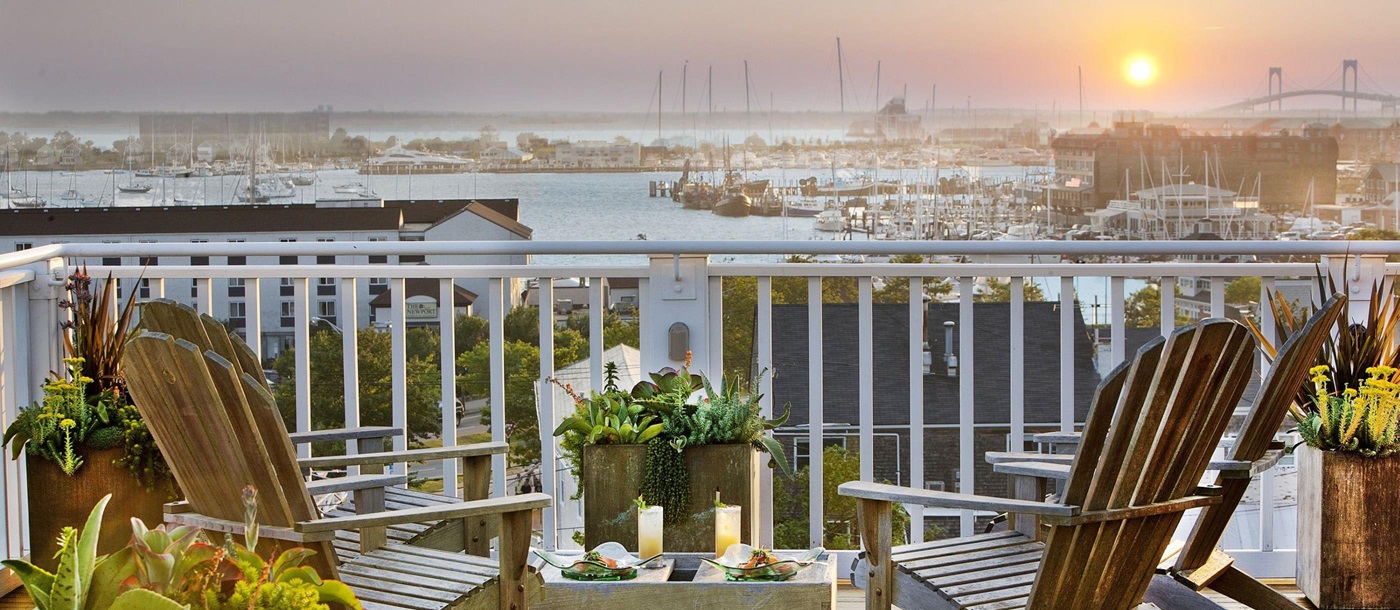 Sun loungers on a balcony viewing the sunset over Newport Harbor from Vanderbilt Grace, USA