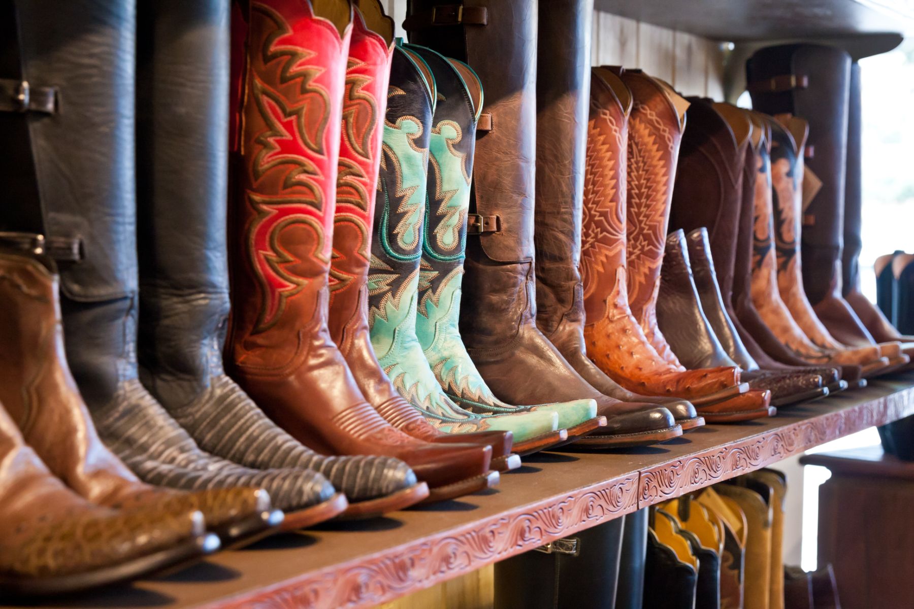 Row of different coloured cowboy boots on display in a shop